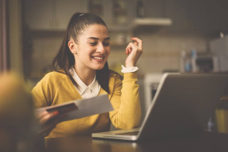 Studentin schaut auf Laptop und freut sich