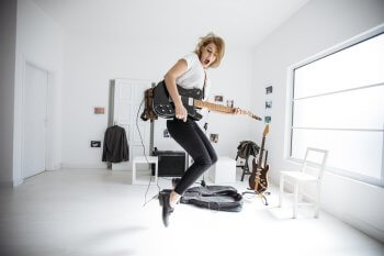Studentin springt mit elektrischer Gitarre